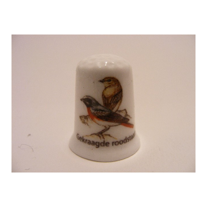 Gekraagde roodstaart zangvogel Phoenicurus phoenicurus op een porselein vingerhoedje