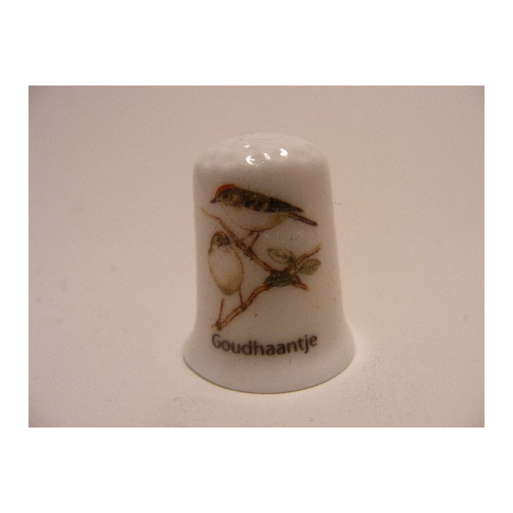 Goudhaantjes zangvogel Regulus op een porselein vingerhoedje