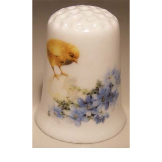 Paaskuiken met ei en bloemen op een vingerhoedje