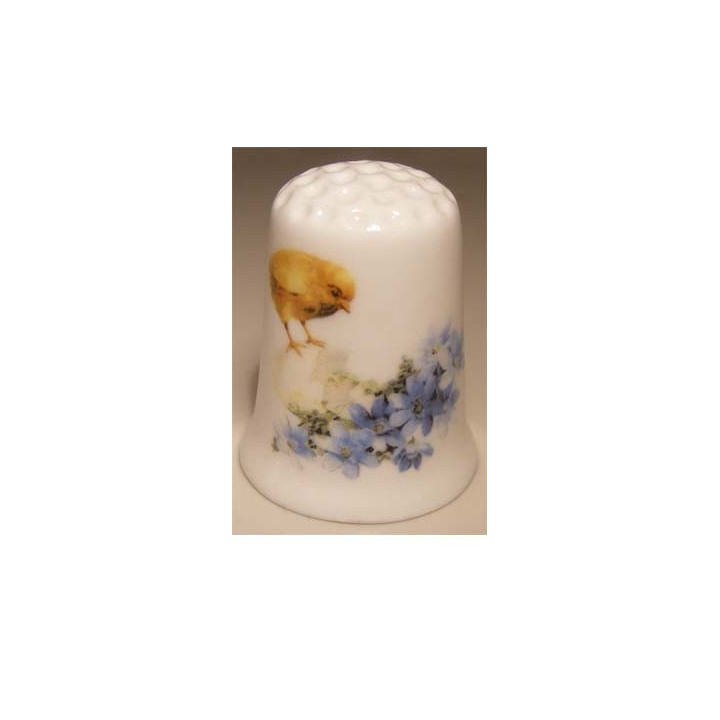 Paaskuiken met ei en bloemen op een vingerhoedje