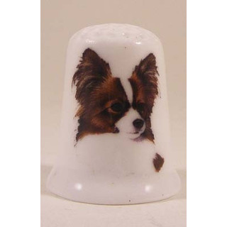 Papillon hond op een porselein vingerhoedje