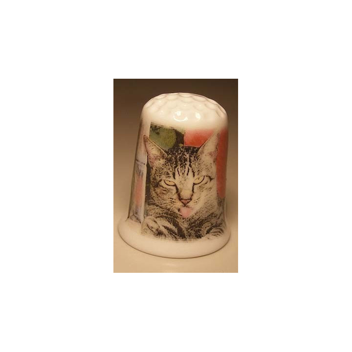 Poes met tong uit bek op een porselein vingerhoedje