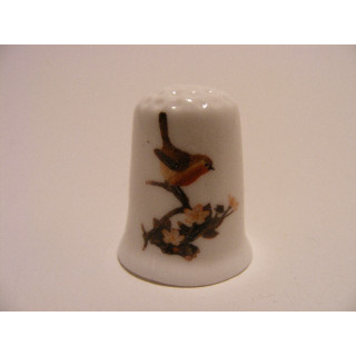 Roodborstje op tak op een porselein vingerhoedje