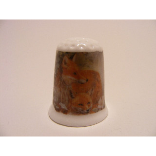 Vos met jong liggend op een porselein vingerhoedje