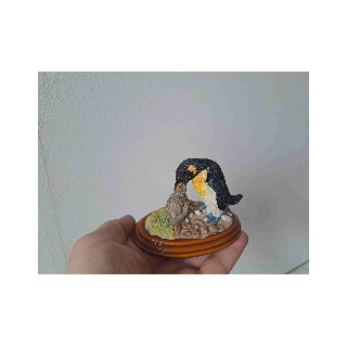 Koningspinguin geeft zijn jong eten op een houten plateau