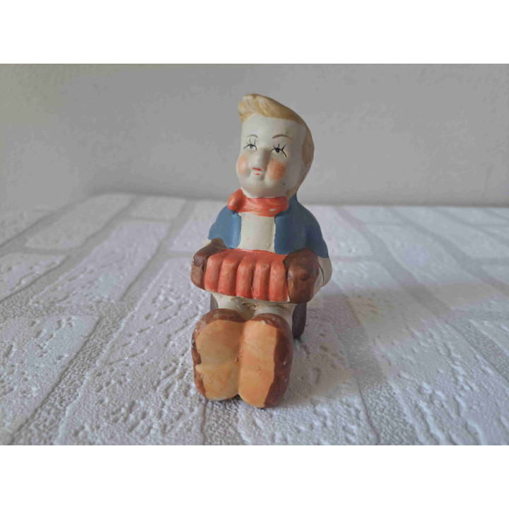 Jongen zittend op de grond speelt op een accordeon