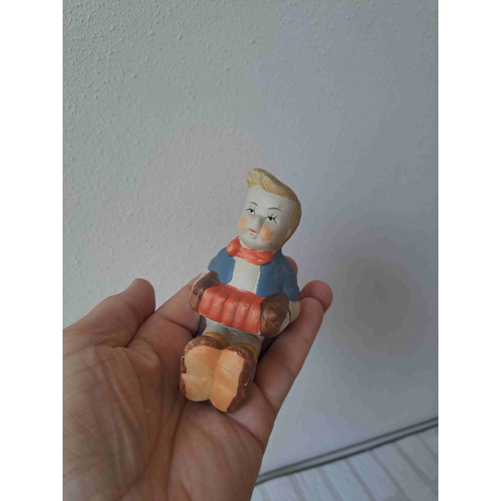 Jongen zittend op de grond speelt op een accordeon