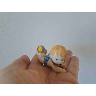 Kind van kunsthars met strandbal op zijn voet