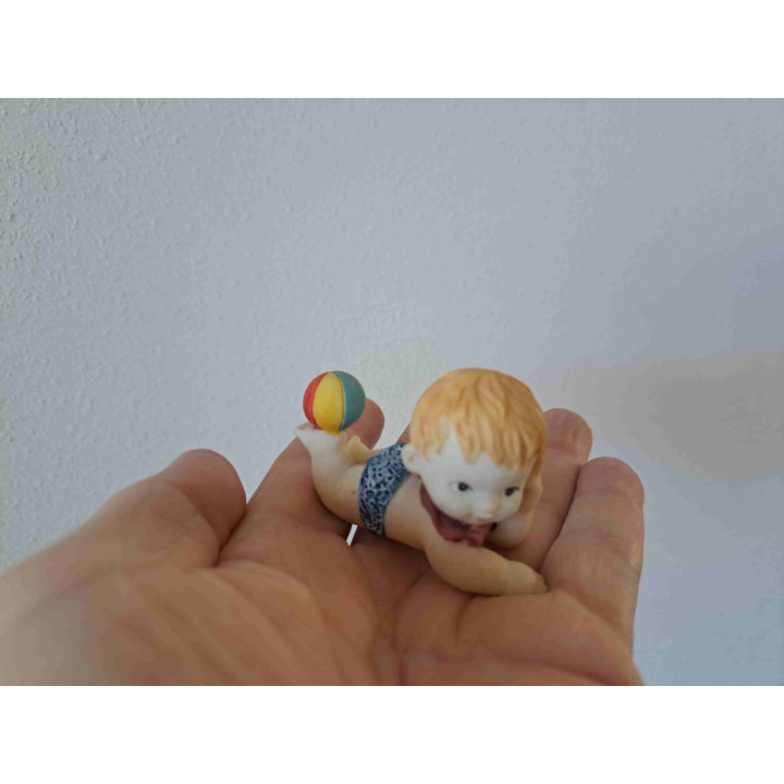 Kind van kunsthars met strandbal op zijn voet