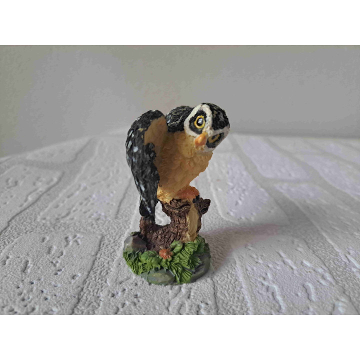 Uil met open vleugels staand op een tak van kunsthars