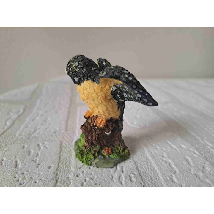 Uil met open vleugels staand op een tak van kunsthars