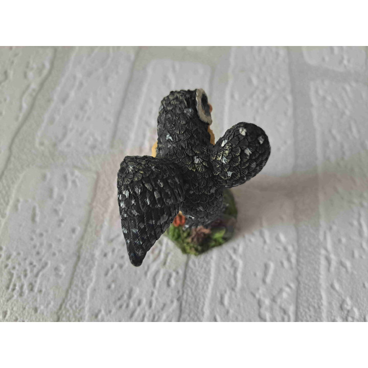 Uil met open vleugels staand op een tak van kunsthars