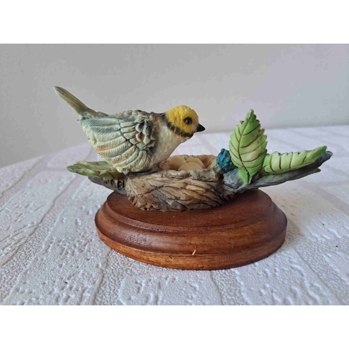 Oranjekoptangare vogel op een nest met eieren van kunsthars en hout - dierfiguren