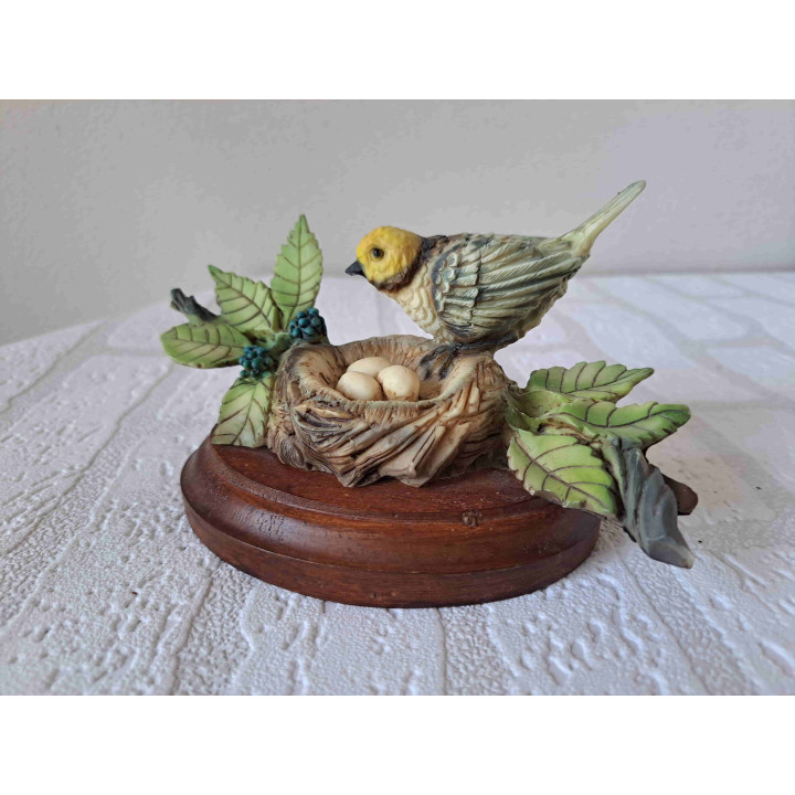 Oranjekoptangare vogel op een nest met eieren van kunsthars en hout - dierfiguren