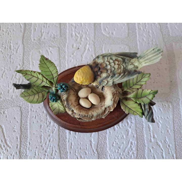 Oranjekoptangare vogel op een nest met eieren van kunsthars en hout - dierfiguren