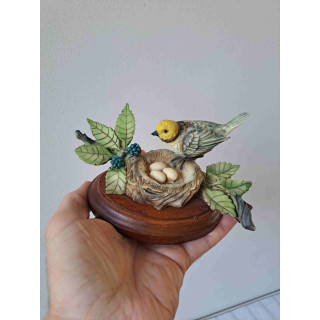 Oranjekoptangare vogel op een nest met eieren van kunsthars en hout