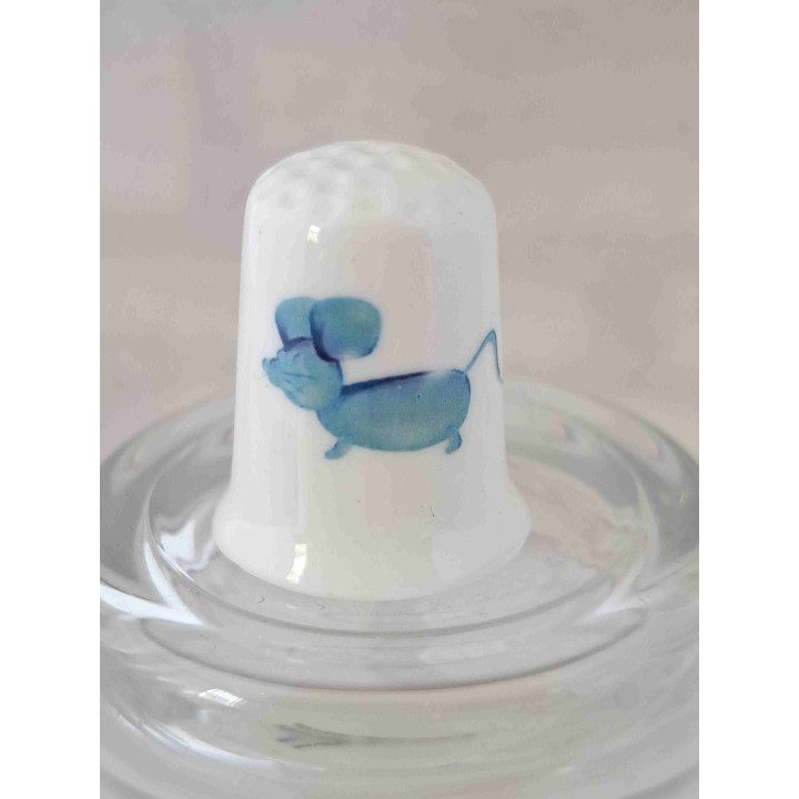 Blauwe muis van glas op een porselein vingerhoedje