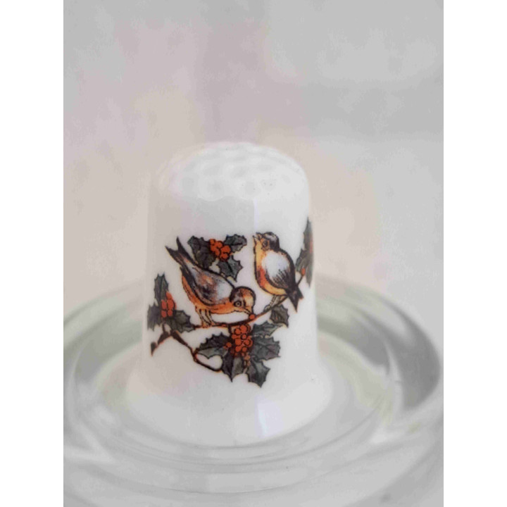 Roodborstjes vogels op kersttak op een porselein vingerhoedje