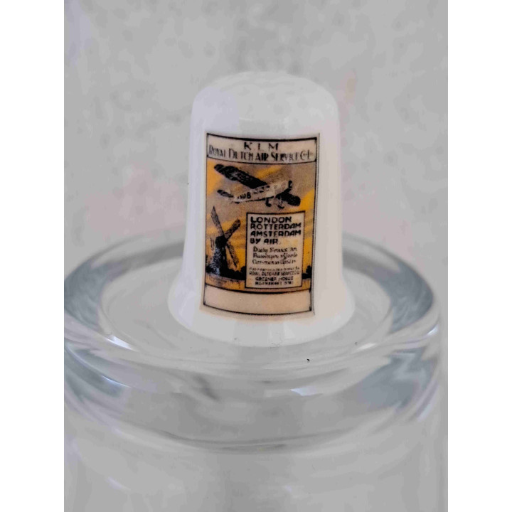 KLM reclame met Fokker F.VII vliegtuig en molen op een vingerhoedje KLM reclame met Fokker F.VII vliegtuig en molen op een vingerhoedje